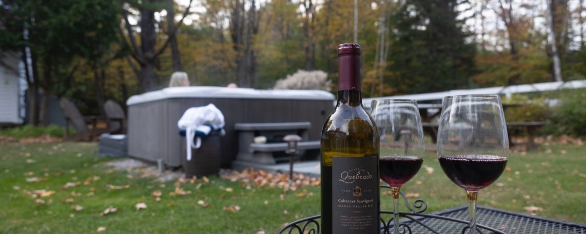 Bottle of wine and glasses on table next to hot tub