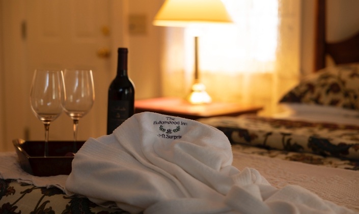 Bathrobe and tray with bottle of wine on the end of the bed